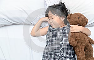 Cute girl sleeping on bed with teddy bear