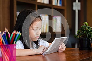 Cute girl smile sitdown and playing tablet smartphone in the lib