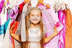 Cute girl standing between hangers during shopping