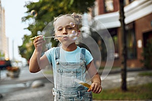 Calm little girl blowing soap bubbles stock photo