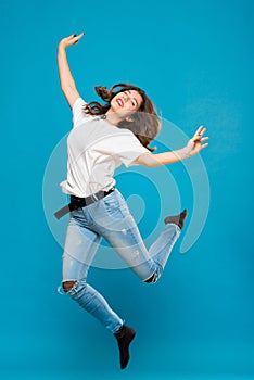 Cute girl student teenager jumping waving hands with a smile on her face on a blue background. The concept of happiness, carefree