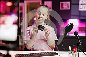 Cute girl in studio reviewing gaming mouse in front of camera in neon lit studio