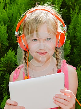 Cute girl with tablet pc listening music in headph