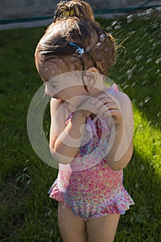 Cute girl is taking a shower outdoor with expression on face