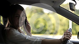 Cute girl talking on the phone behind the wheel of the car