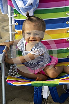 Cute girl toddler in a colorful beach chair