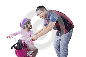 Cute girl trains to ride a bicycle with dad