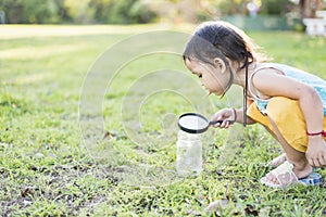 Cute girl using magnifying glass to look at bugs in glass jars Learn to use science-related observations