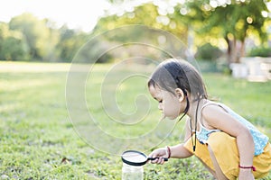 Cute girl using magnifying glass to look at bugs in glass jars Learn to use science-related observations