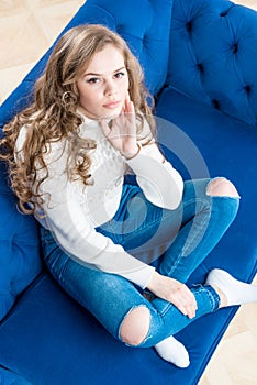Cute girl in a warm sweater on the couch in the living room view