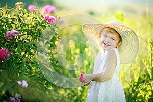 Cute girl wearing hat and white dress stand in the pink flower field of Sunn Hemp Crotalaria Juncea