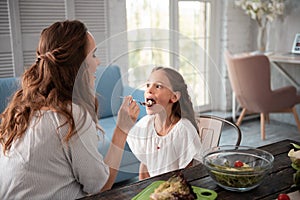 Cute girl wearing white blouse eating chocolate spread from spoon