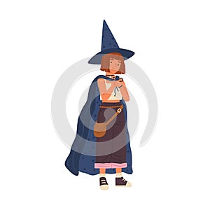 Cute girl wearing witch hat and cloak. Smiling child in costume for Halloween. Portrait of wizard, sorcerer putting on