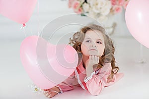 Cute girl on white floor in studio with a bunch of pink balloons