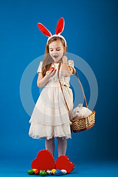 Cute girl with White rabbit in basket with Easter eggs