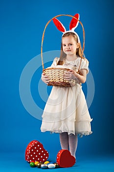 Cute girl with White rabbit in basket with Easter eggs