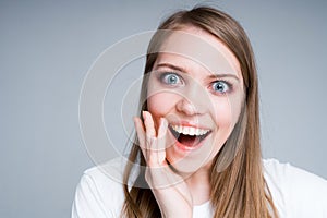 Cute girl in a white T-shirt is surprised opening her mouth and putting her hand to her face photo