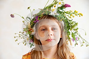 Cute girl with  wreath of summer wild flowers