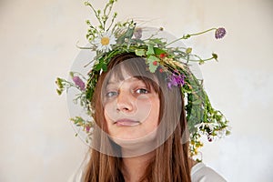 Cute girl with  wreath of summer wild flowers