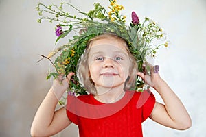 Cute girl with  wreath of summer wild flowers