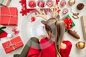 Cute girl writing letter to Santa on livingroom floor. Overhead view of a young girl writing her christmas wishlist.