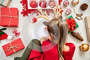 Cute girl writing letter to Santa on livingroom floor. Overhead view of a young girl writing her christmas wishlist. photo