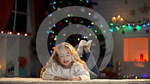 Cute girl writing letter to Santa lying on floor, belief in magic fairy-tale