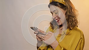 Cute girl in yellow light, laughs, smiles and looks at the camera. A teenager with accessories and a hoop on his head.