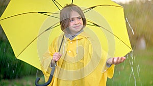 Cute girl in a yellow raincoat with an umbrella