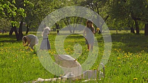 Cute girls in beautiful striped dresses are walking on the lawn in the garden