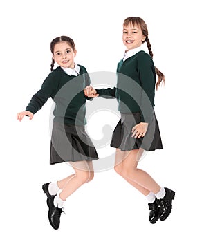 Cute girls in school uniform jumping on white