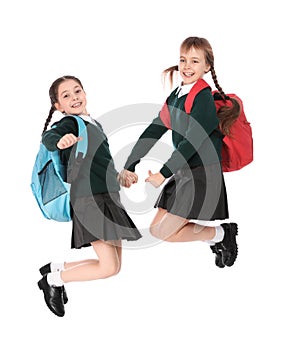 Cute girls in school uniform jumping on white