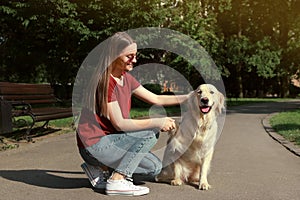 Cute golden retriever dog giving paw to young woman in park