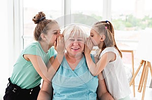 Cute granddaughters sharing secret with grandmother