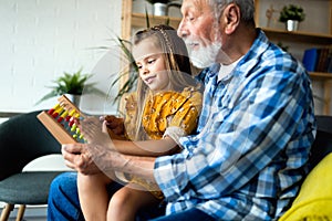 Cute grandfather and beautiful grandchildren reading a book