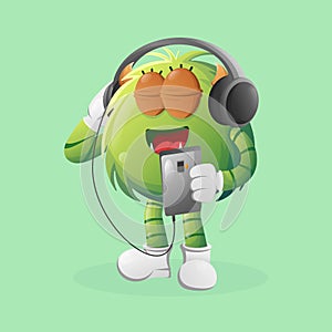 Cute green monster listening music on a smartphone using a headphone