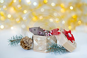 Cute grey little rat-mouse in a New Year`s red-white scarf sitting in the wicker box with red-white snowflake