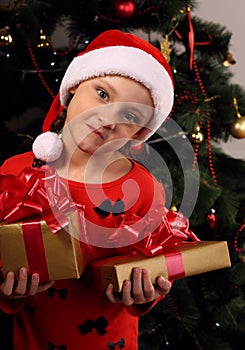 Cute grimacing kid girl in Christmas santa claus hat holding the