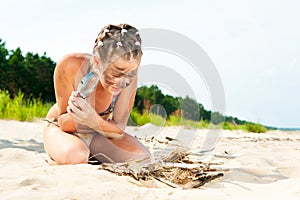 Cute grimy girl lighting fire on the beach with magnifier