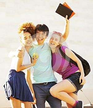 Cute group of teenages at the building of university with books huggings