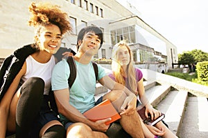 Cute group of teenages at the building of university with books huggings, back to school