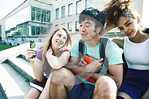 Cute group of teenages at the building of university with books huggings, diversity nations real students lifestyle