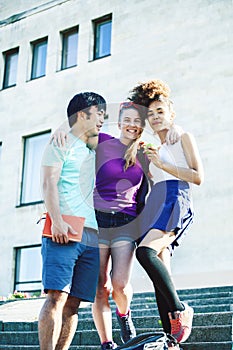 Cute group of teenages at the building of university with books huggings, diversity nations real students lifestyle