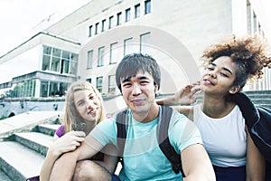 Cute group of teenages at the building of university with books huggings, diversity nations real students lifestyle