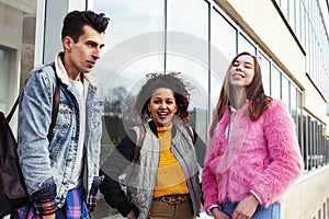 Cute group of teenages at the building of university with books huggings, diversity nations real students lifestyle