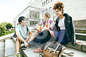 Cute group of teenages at the building of university with books huggings, diversity nations students lifestyle