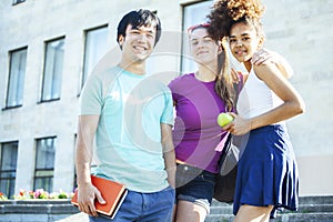 Cute group of teenages at the building of university with books huggings, diversity nations students lifestyle