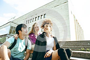 Cute group of teenages at the building of university with books huggings, diversity nations students lifestyle