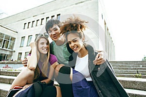 Cute group of teenages at the building of university with books huggings, diversity nations students lifestyle