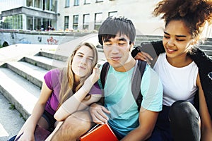 Cute group of teenages at the building of university with books huggings, diversity nations students lifestyle